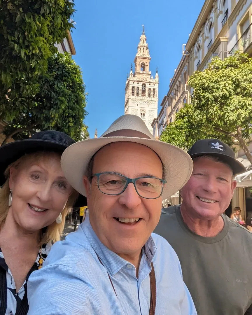 Selfie de turistas sonrientes con la Giralda de Sevilla al fondo, acompañados por el guía Carlos Rodríguez Silva.