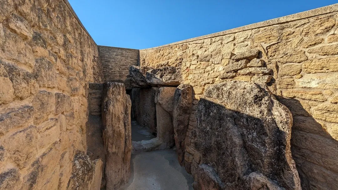 Entrada al Dolmen de Viera durante una visita guiada a los Dólmenes de Antequera con muros de piedra y cielo azul.