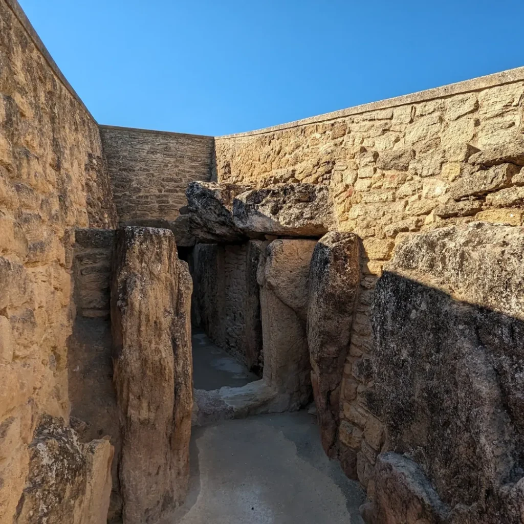 Entrada al Dolmen de Viera durante una visita guiada a los Dólmenes de Antequera con muros de piedra y cielo azul.